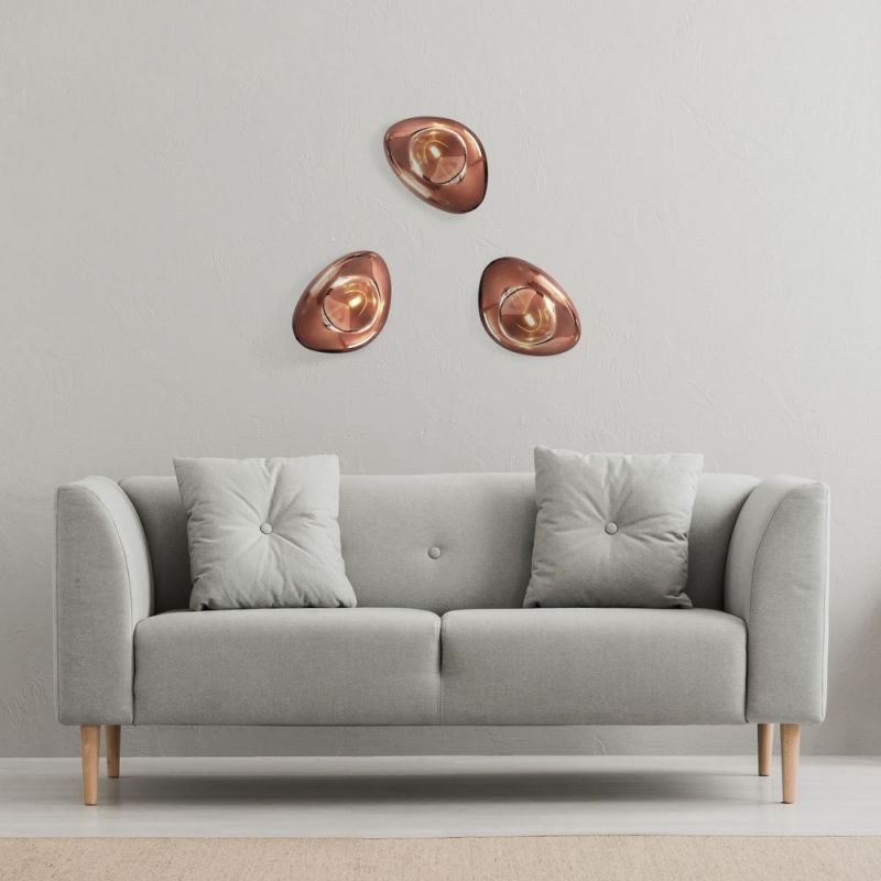 Three glass wall lights in copper arranged in a group above the couch