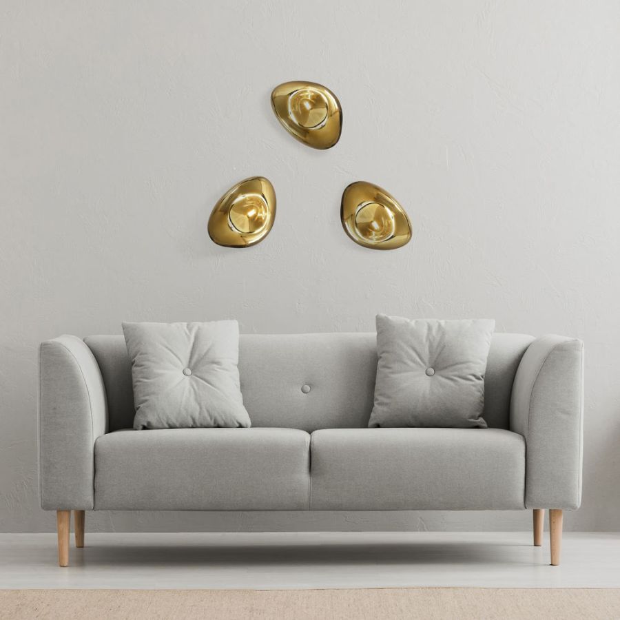 Three golden wall lights in a group above the couch